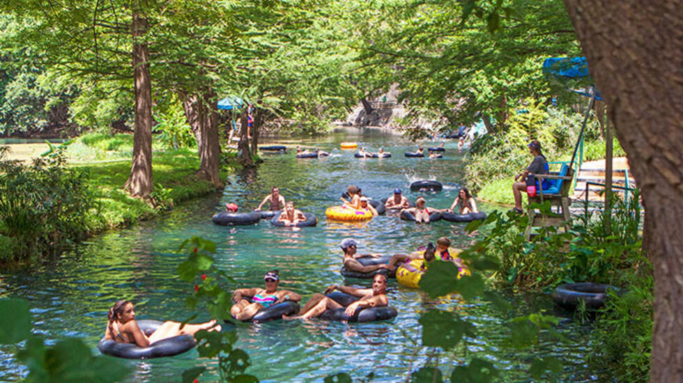 People using inner tubes to float down the Guadalupe river on a sunny summer day